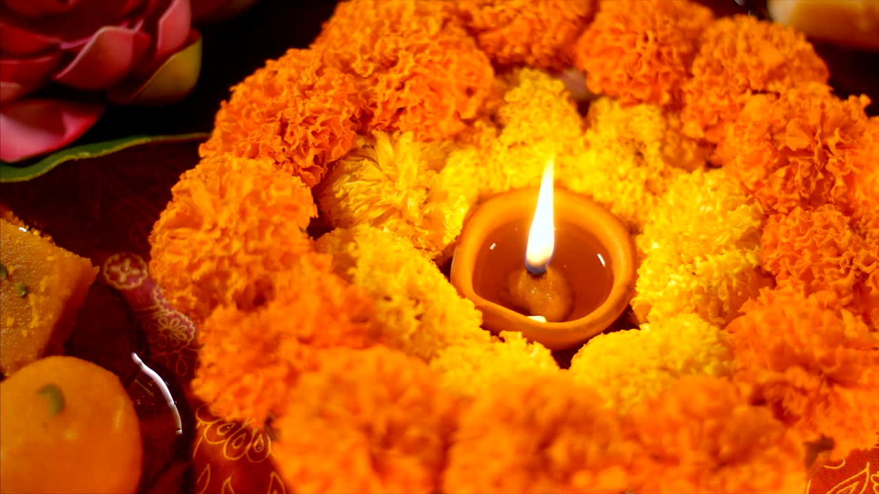 una lámpara de diya encendida durante la celebración de diwali puja con flores y dulces