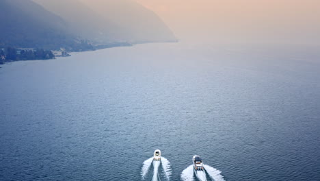 aerial drone back view of two speed boats racing on lake