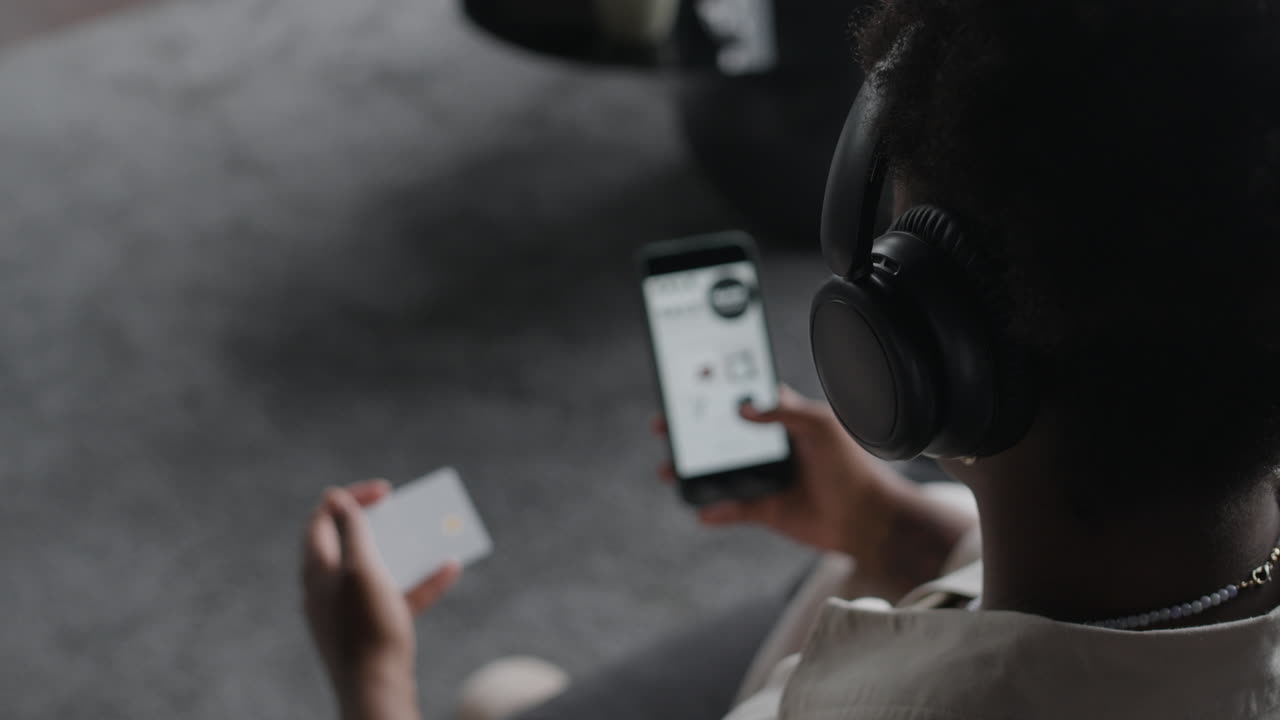 Person using smartphone with headphones and credit card