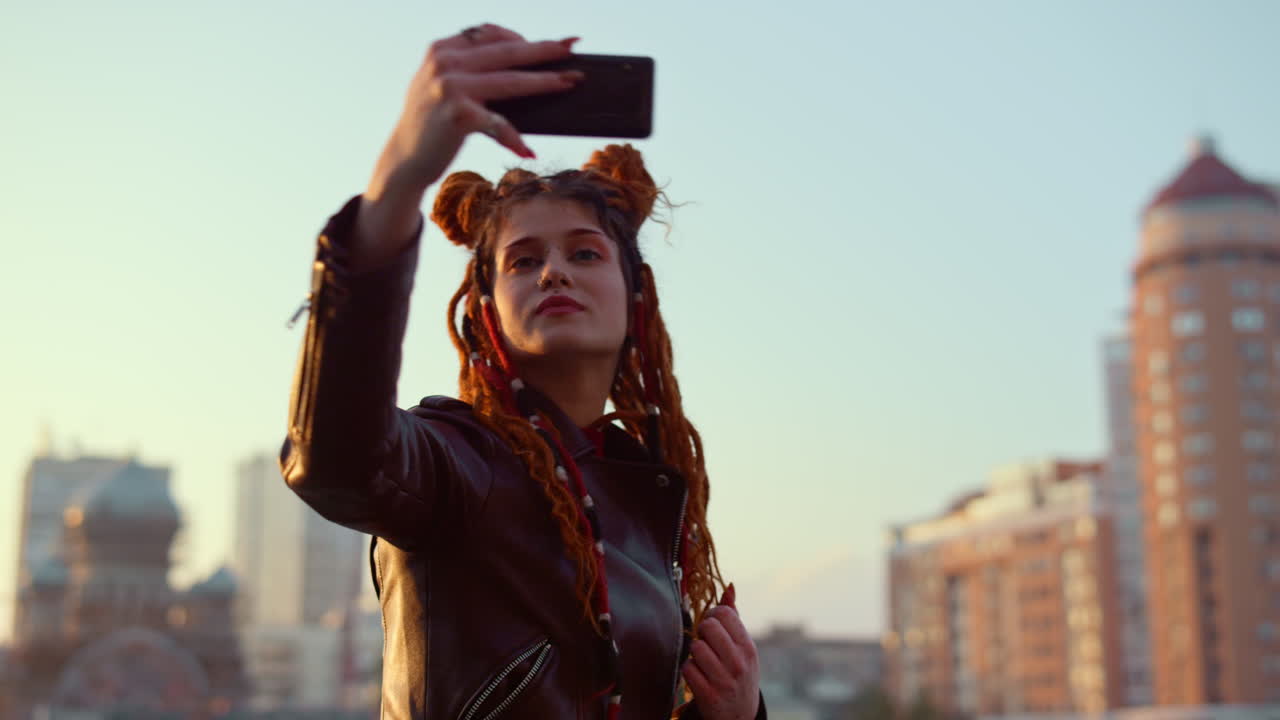 Young woman posing for phone camera outside. Girl making video on cellphone.