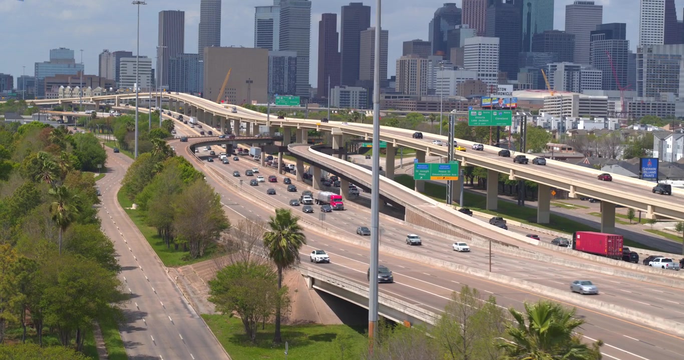 This drone view captures the I 45 South freeway with cars flowing toward the downtown Houston, Texas skyline in the background.