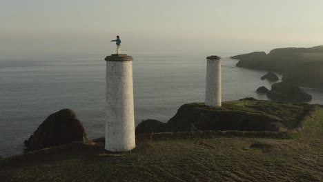 sunset aerial: tower beacon metal man points out to sea in ireland