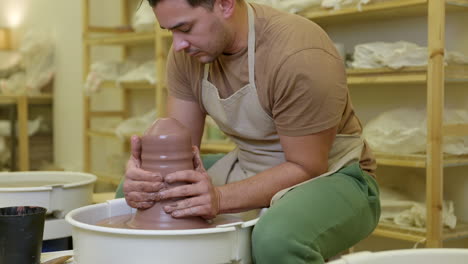 small business potter shaping clay spinning on pottery wheel in studio workshop