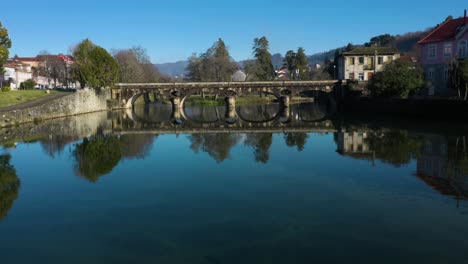 aerial dolly establishes old roman bridge reflecting perfect circles in river vez in town of arcos de valdevez in portugal