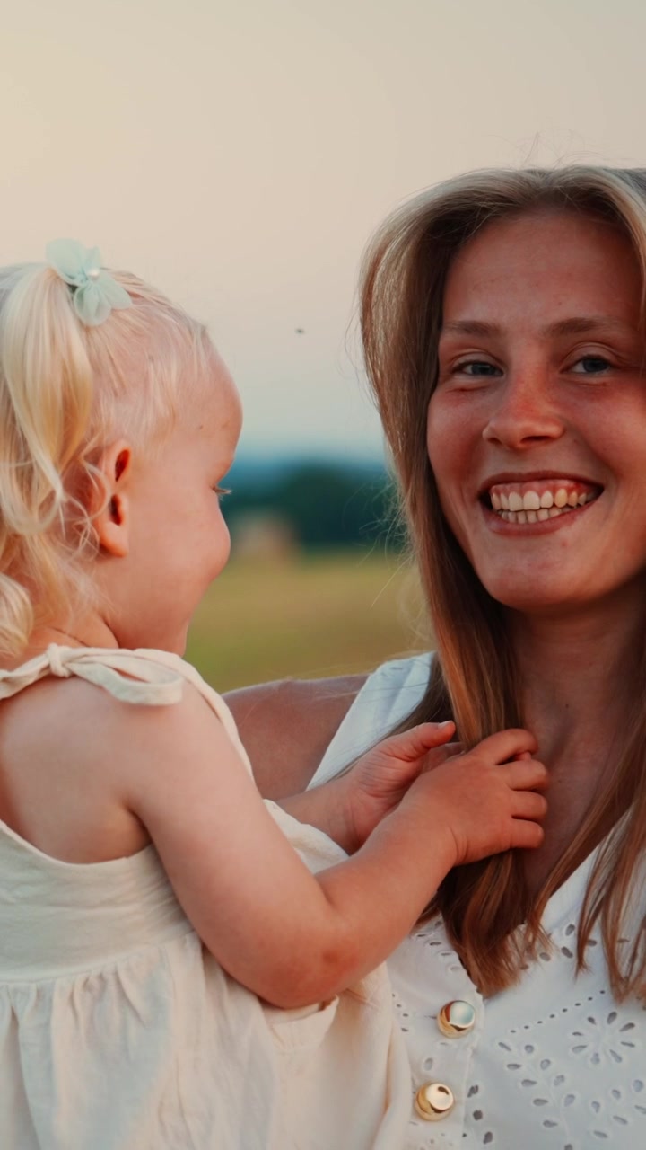 Glückliche Mutter hält ihre kleine Tochter im Freien bei Sonnenuntergang