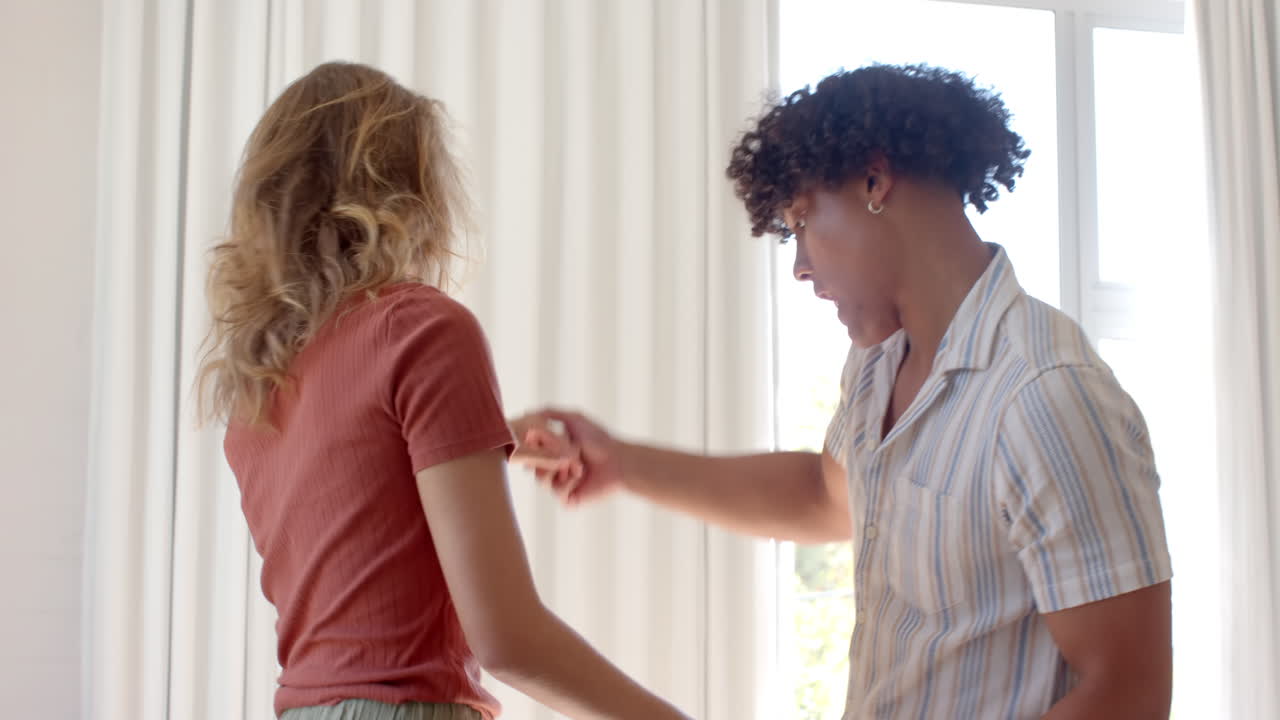 Diverse couple dancing joyfully at home, enjoying each other's company and smiling