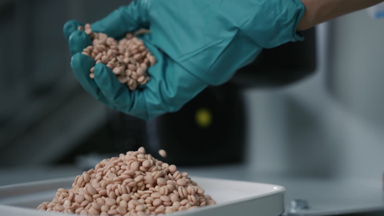 Slow motion shot of a hand pouring coolant granules slowly into a bowl in front of a milling machine