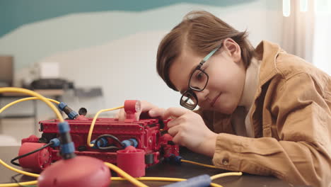 caucasian schoolboy constructing robot during science lesson