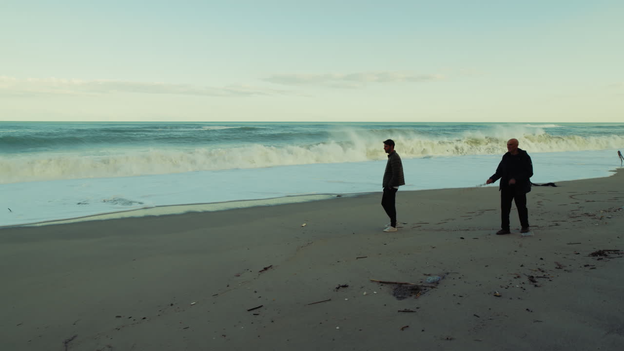Elderly Father Walks With Son Near Stormy Ocean Waves