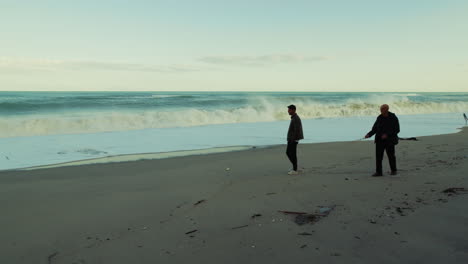elderly father walks with son near stormy ocean waves