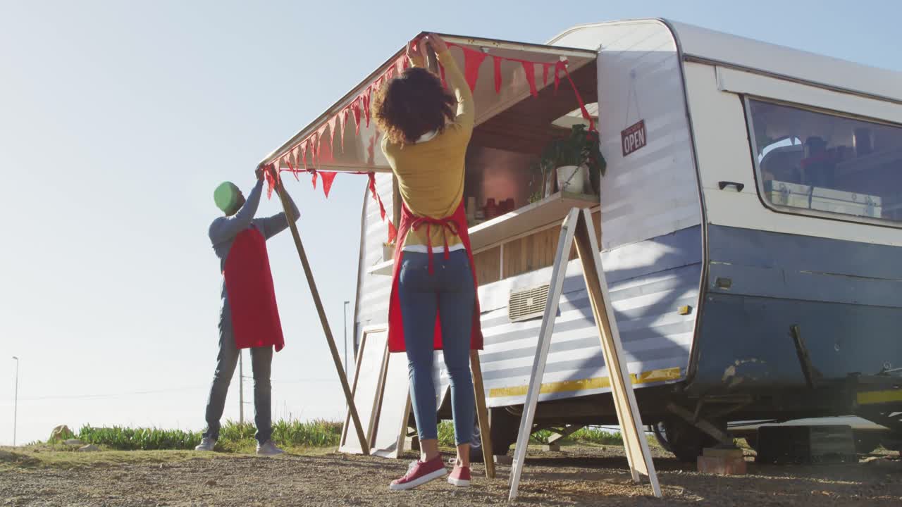 아프리카계 미국인 부부가 길거리에서 음식 트럭을 설치하고 있습니다.