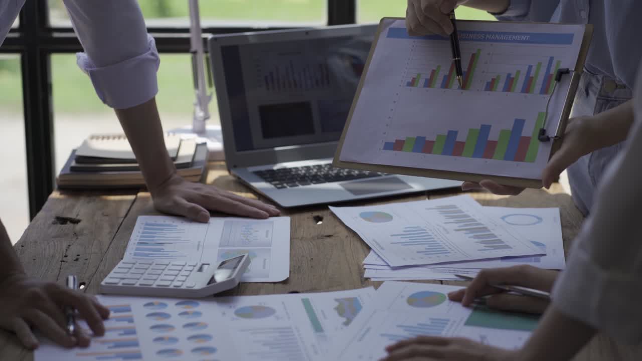 Close-up of a financial analyst and a planning team of young entrepreneurs discussing project ideas using papers to brainstorm modern business firms.