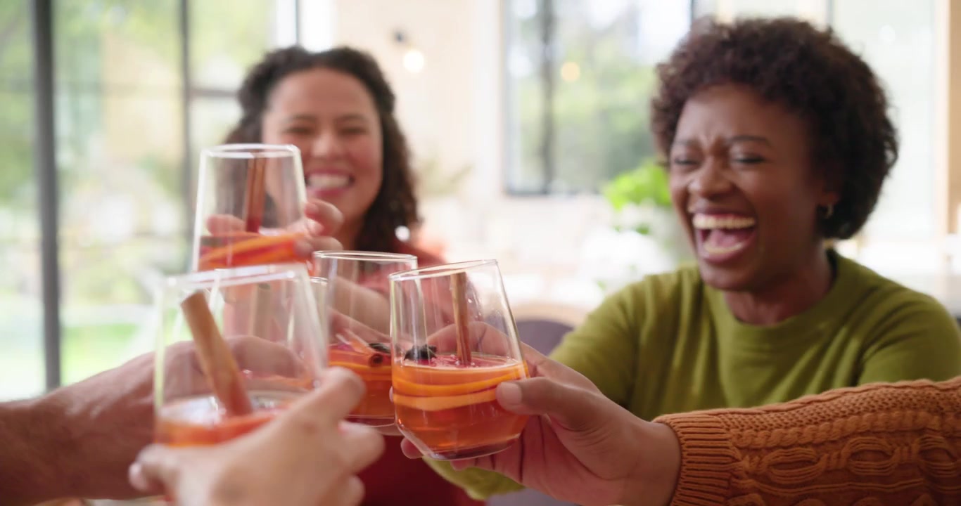 Amici di diverse etnie che brindano con cocktail a una cena a casa