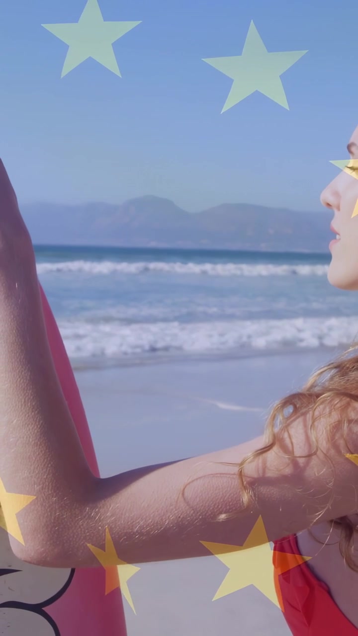 Video verticale: Donna con tavola rosa che si gira verso la riva mentre la telecamera esegue una panoramica, con sovrapposizione di stelle per il tema viaggio