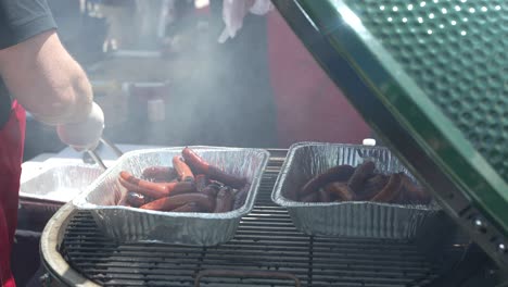 chef taking out grilled sausages from smoker.