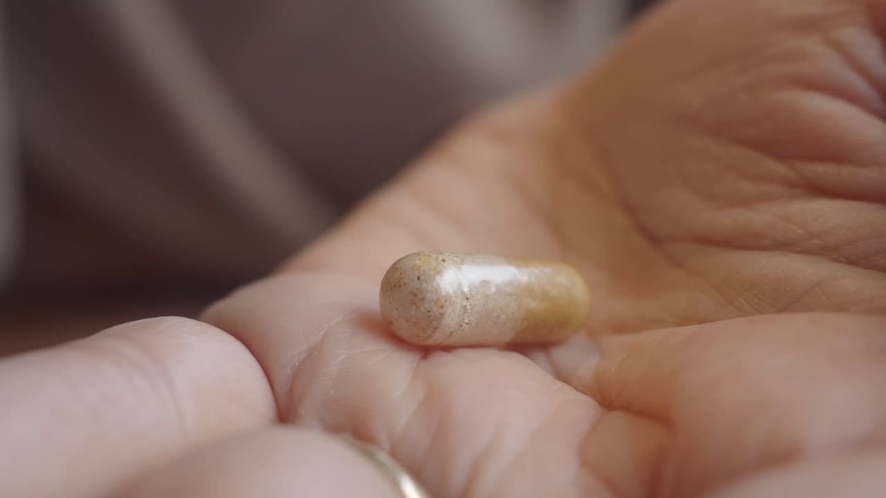 Primo piano di una mano che prende una capsula.