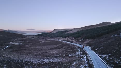 Vehículo-Solitario-Conduciendo-A-Través-De-Un-Paisaje-Accidentado-En-La-Isla-De-Skye-Al-Atardecer,-Temporada-De-Invierno,-Vista-Aérea