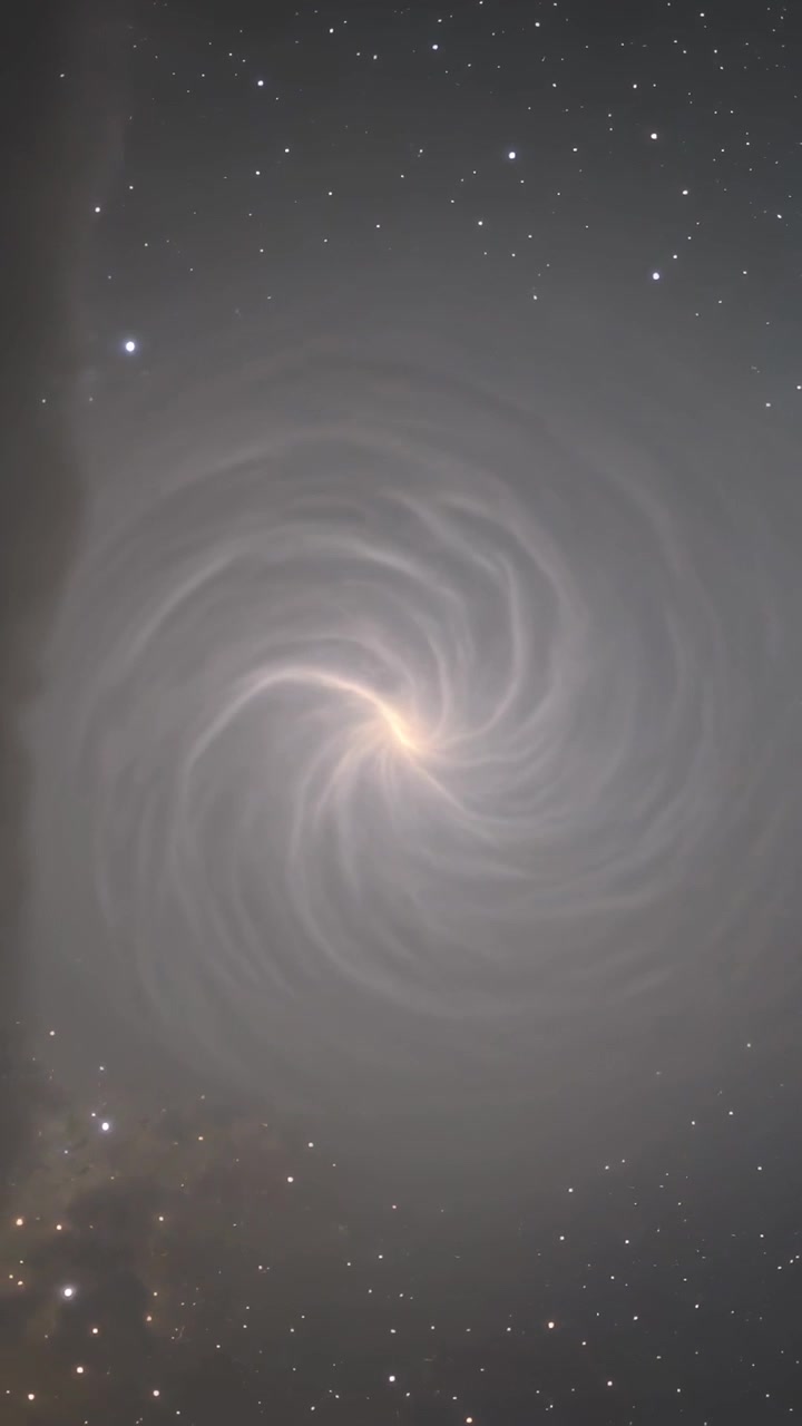 Video verticale: Vortice rotante che si sposta dopo un'inquadratura nel cielo notturno, mostrando bracci a spirale e una banda scura