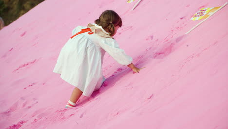 little girl climbs up on pink sand hill at herb island park, pocheon, korea