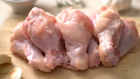 Alas de pollo crudo fresco sobre tabla de madera con ingredientes