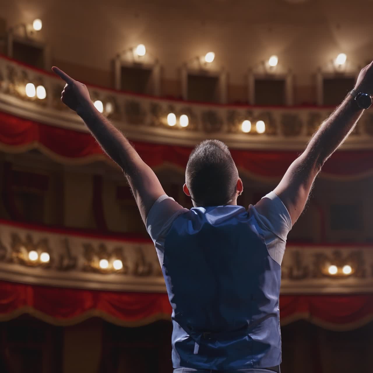 Man performing with gestures on stage. Unrecognizable actor standing on stage in classic theater. Male actor speaks from the scene. Back view.
