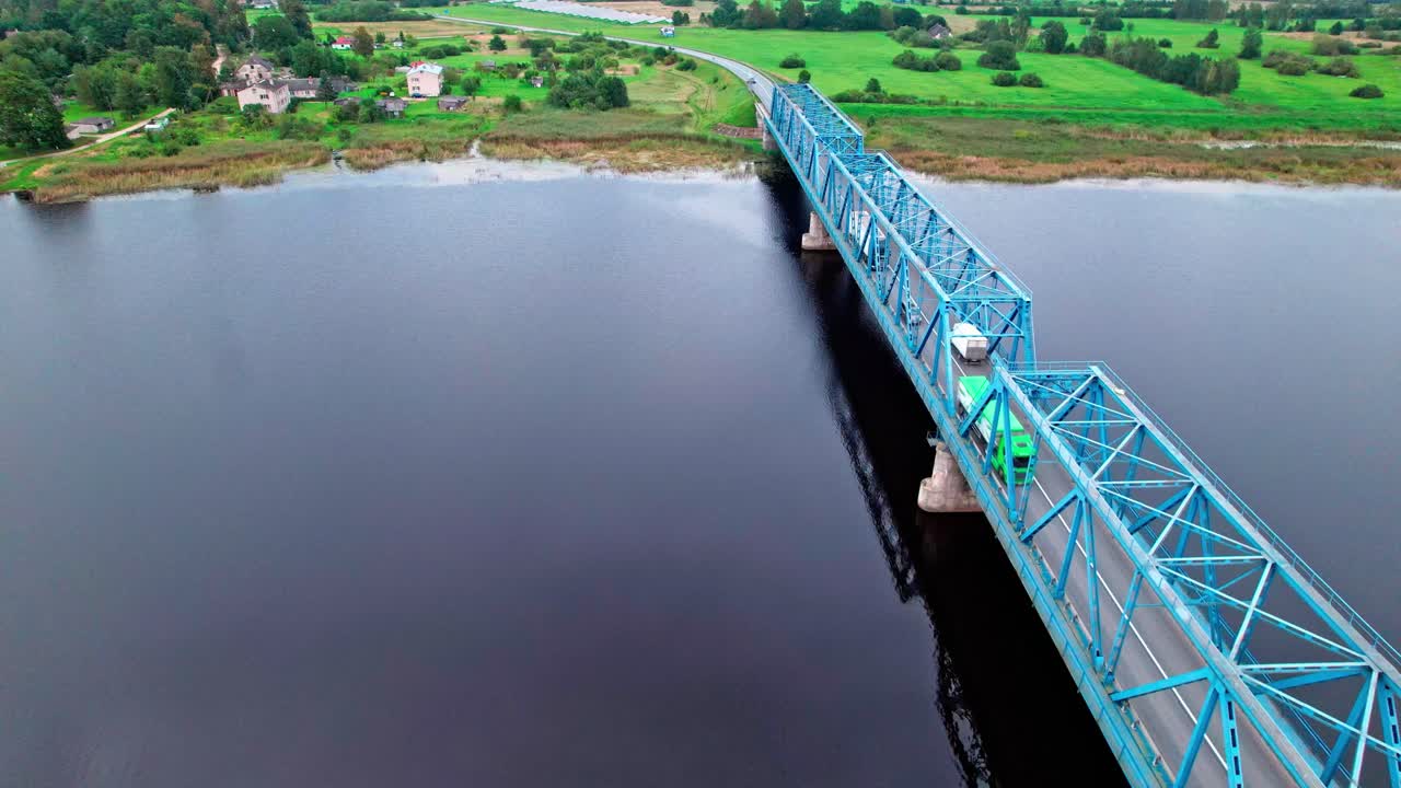 Blue bridge spans calm river in rural Latvia