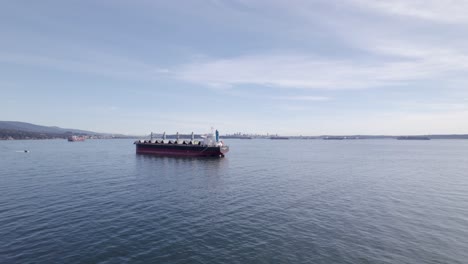 aerial shot flying past a cargo ship about to dock, vancouver canada