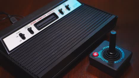 close-up of vintage tv video game console computer with joystick on wooden table.