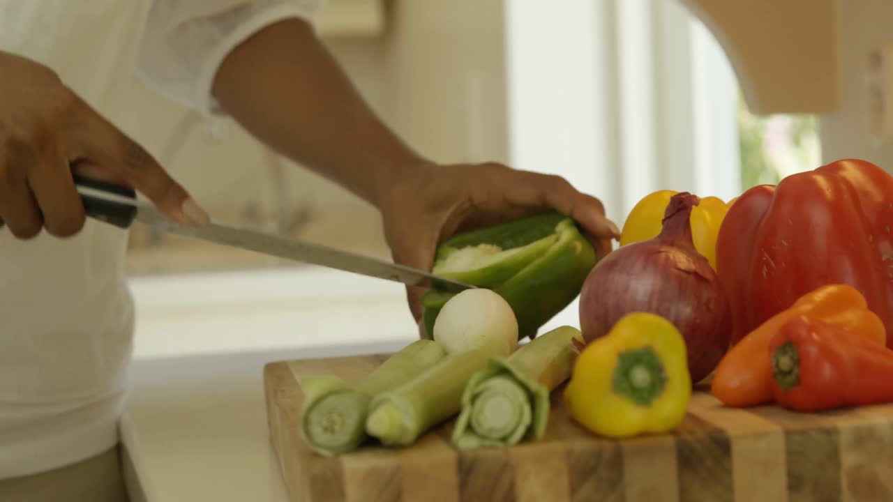 sección media de una mujer cortando verduras en la cocina