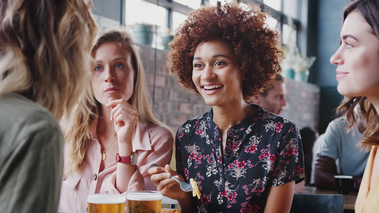 Quattro giovani amiche che si incontrano per bere e mangiare al ristorante.