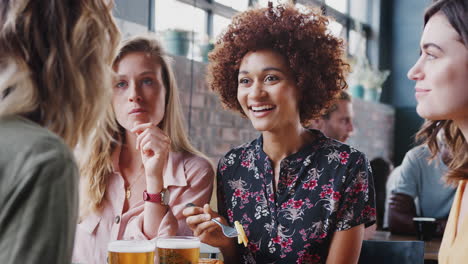 four young female friends meeting for drinks and food in restaurant