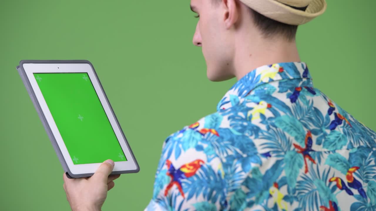 Profile view of young handsome tourist man using digital tablet