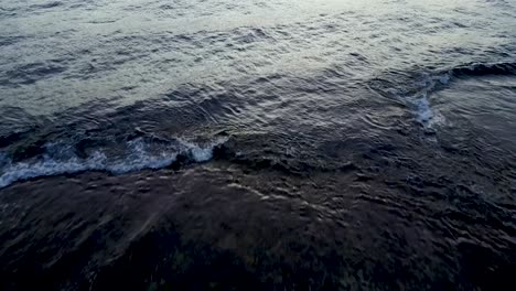 backward drone aerial revealing multiple waves clashing and drifting on fiji shores