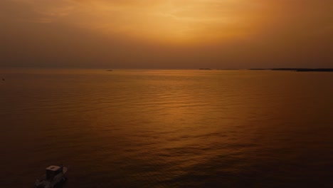 Volando-Hacia-Atrás-Sobre-Un-Yate-De-Vacaciones,-Un-Barco-De-Pesca-Junto-A-La-Hermosa-Bahía-Costera-De-Puesta-De-Sol-Naranja-Y-Roja-En-El-Idílico-Mar-Mediterráneo-Adriático-Junto-A-La-Costa-Croata