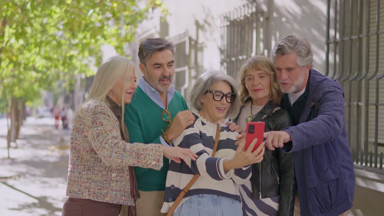 Grupo de personas mayores usando un smartphone juntos en la acera de la ciudad