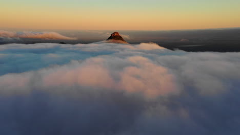 Antena,-Disparo-De-Drones-Que-Se-Eleva-Sobre-Las-Nubes-Hacia-Un-Pico-De-Montaña-Iluminado-Por-El-Sol,-Durante-La-Puesta-De-Sol,-En-El-Parque-Nacional-Hassell,-Australia-Occidental