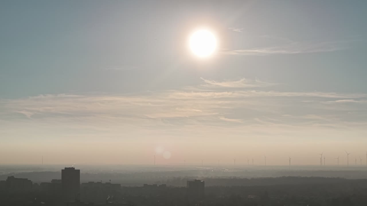 Bright sun above hazy Berlin capital city skyline creating soft atmospheric urban silhouette, Germany