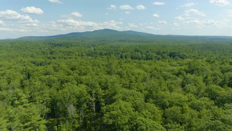 aerial drone forward moving shot over the mountain forest beside sunset lake in new hampshire, usa