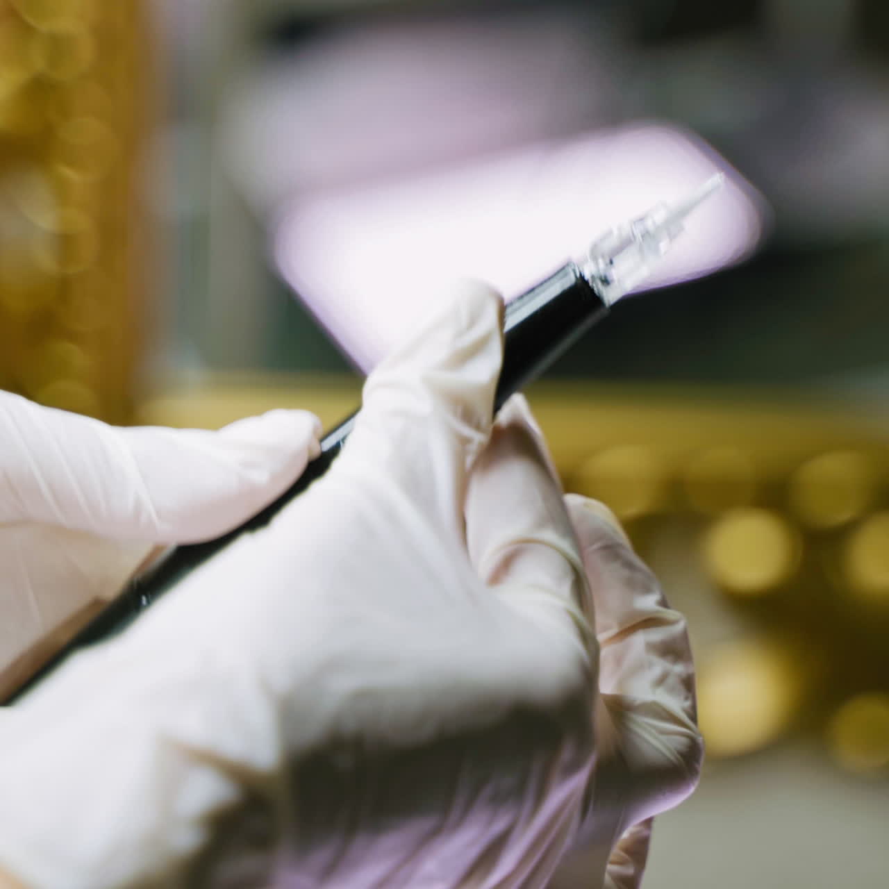 A beautician in white gloves holds pen in her one hand, and other adjusts the device for permanent makeup in a beauty salon before the arrival of the client.