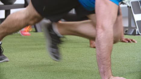 two people work out doing mountain climbers at a gym