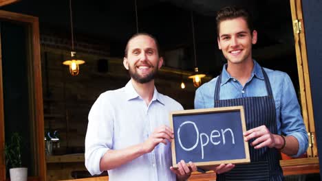 owner and waiter holding open sign board