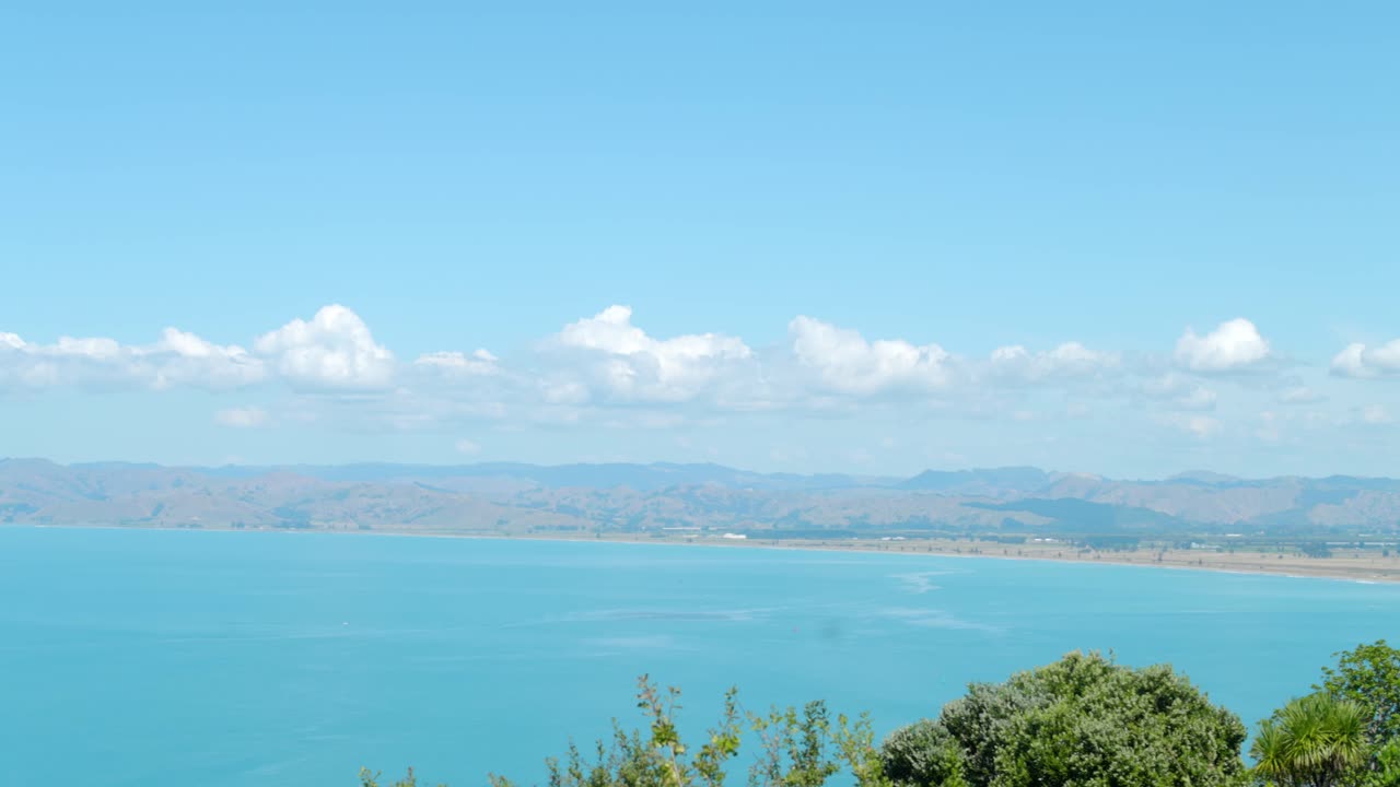 a long panning shot taken from a hilltop looking into the bay of an ocean