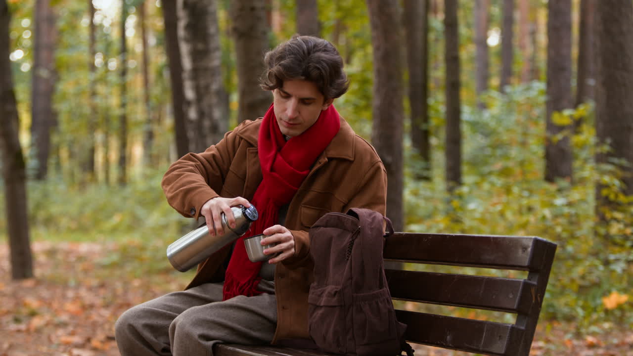 Man with Thermos Sitting on Bench in Autumn Park