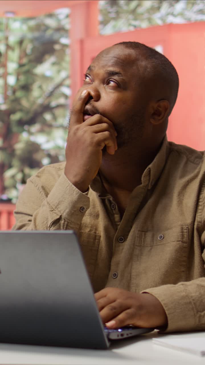 African American Man Working and Thinking on Laptop in Office
