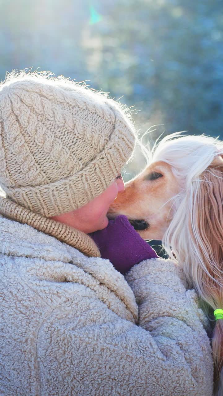 Una donna e il suo levriero afgano condividono un momento d'amore in inverno