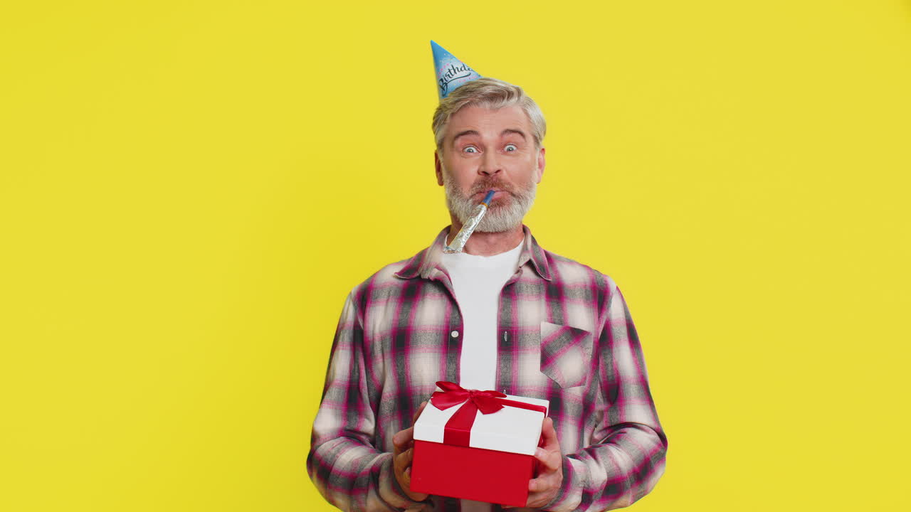 Happy mature man surprise gift moment party cone hat joyful shock red bow birthday excitement