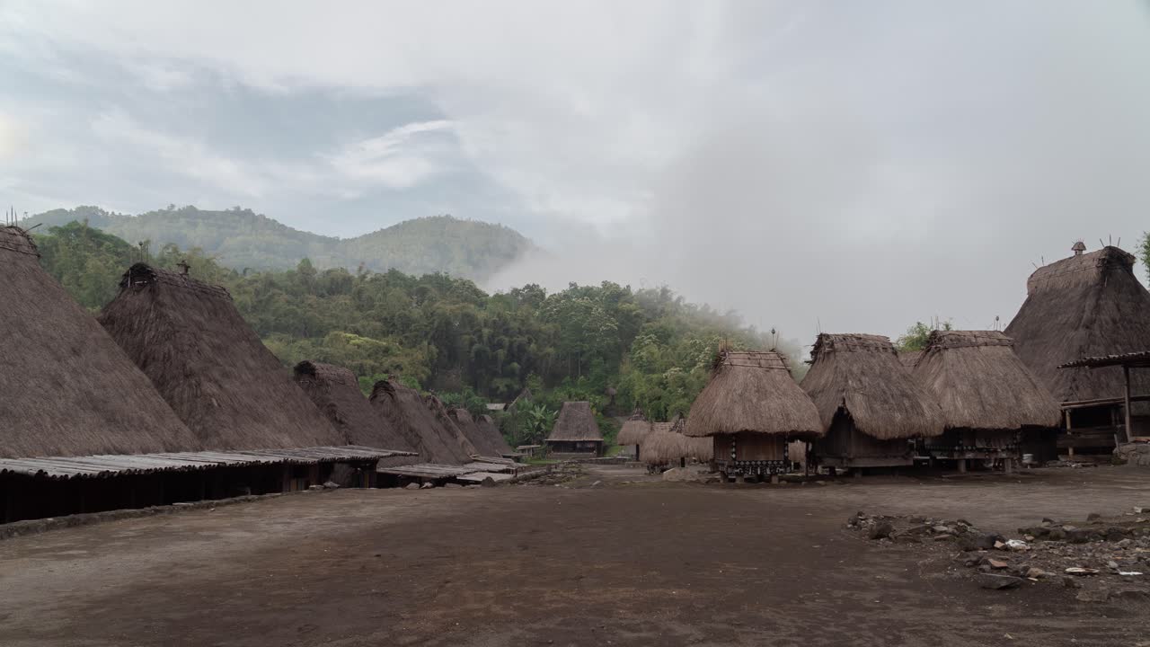 Traditional Village with Thatched-Roofed Houses Nestled in Misty Mountains