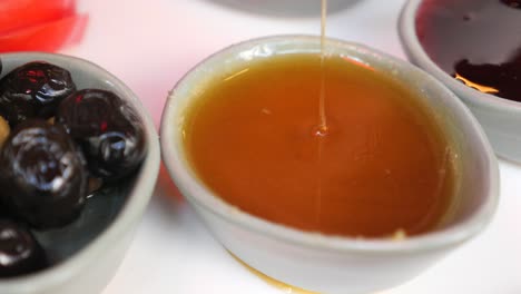 Close up of a honey dip on a plate with olives and jam