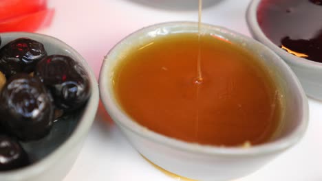 close up of a honey dip on a plate with olives and jam