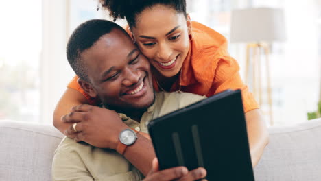 Couple,-tablet-and-smile-with-hug-on-sofa-in-home